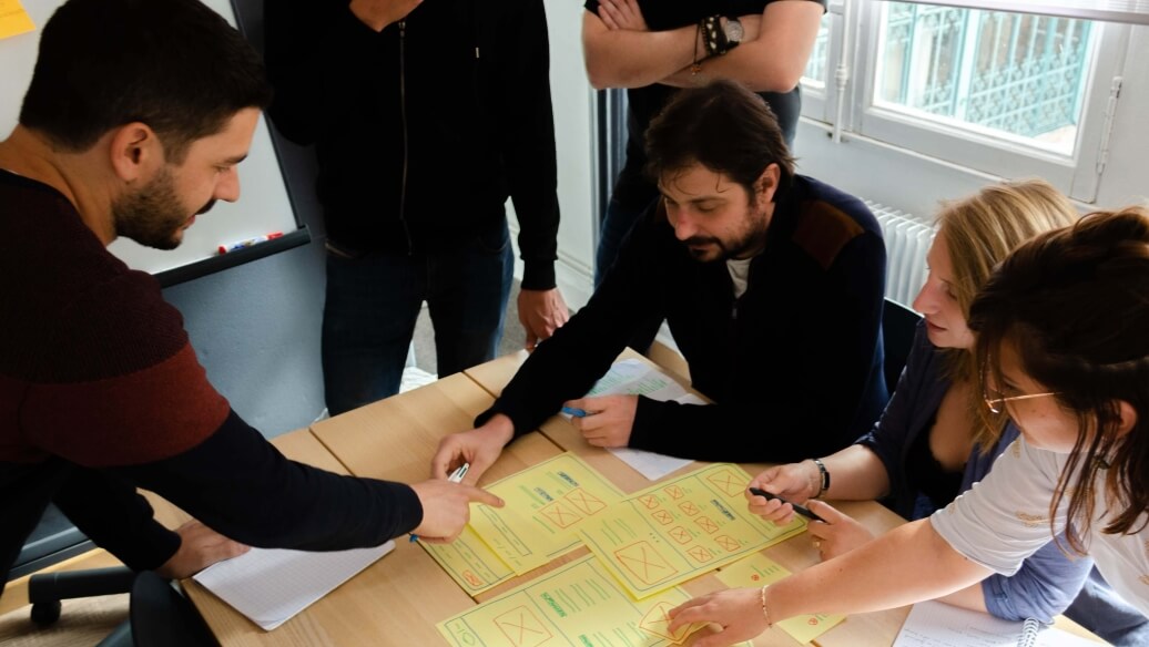Cinq personnes discutent autour d'une table avec des notes jaunes.