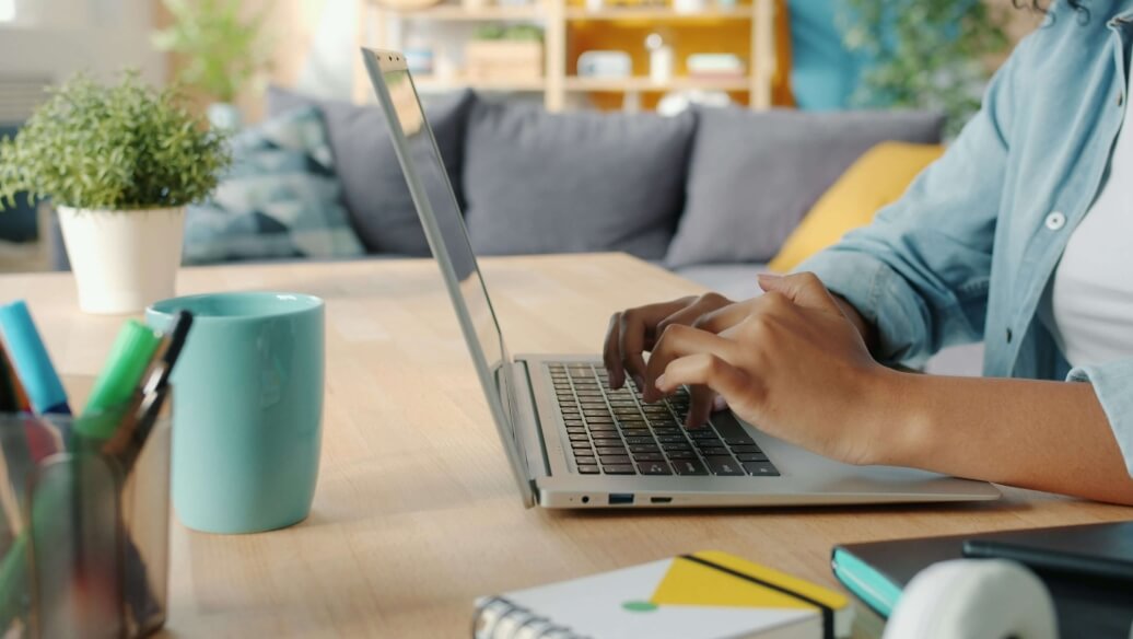 Personne tapant sur un ordinateur portable à une table avec des fournitures de bureau.