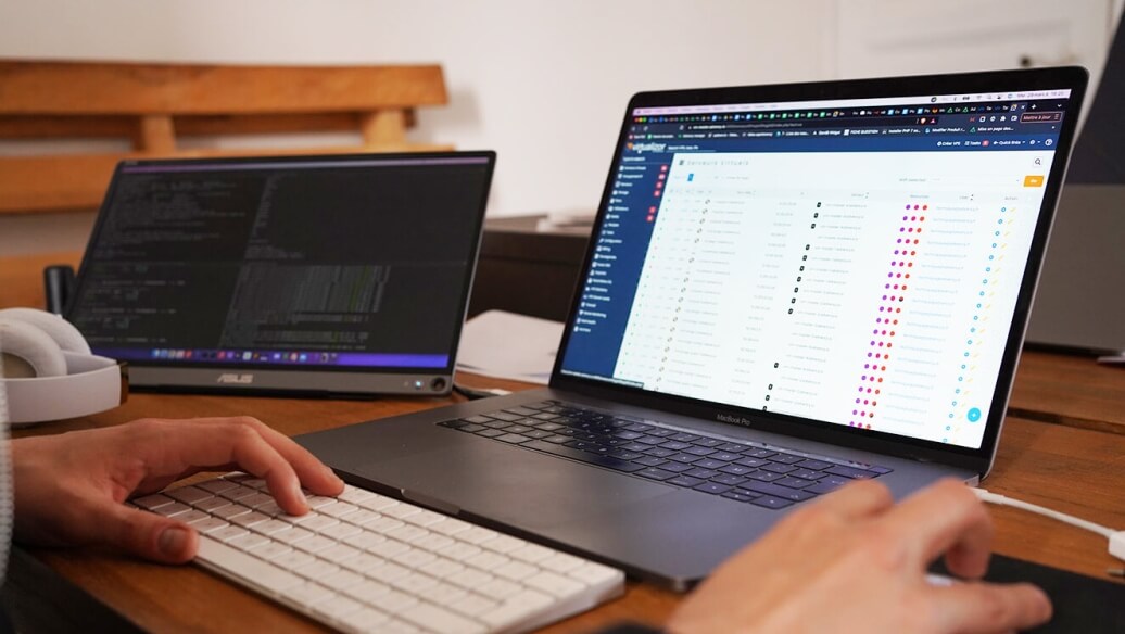 Deux ordinateurs portables sur un bureau en bois, affichant du code et un tableau.