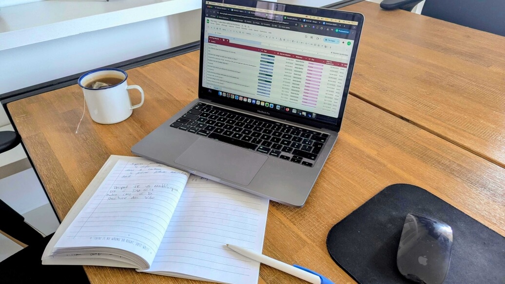 Ordinateur portable sur une table, avec cahier, stylo et tasse de café.