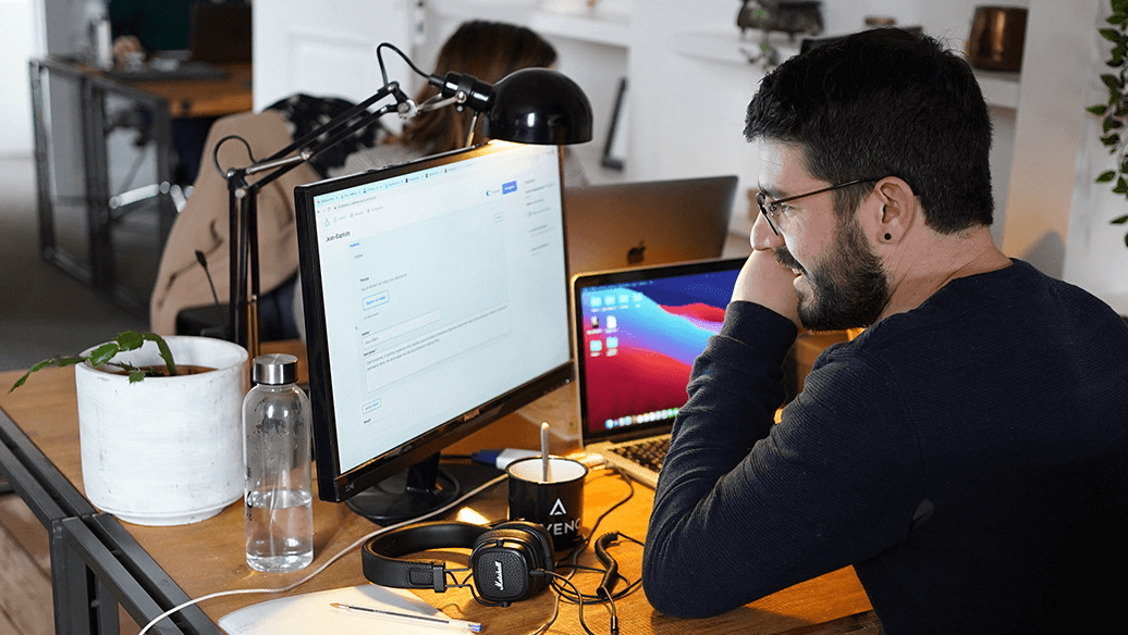 Homme travaillant devant des écrans d'ordinateur dans un bureau moderne.