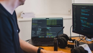 Personne travaillant sur un ordinateur avec des écrans montrant du code.