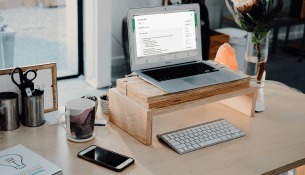 Bureau moderne avec ordinateur portable surélevé, clavier, et plantes.