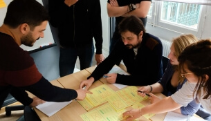 Cinq personnes discutent autour d'une table avec des notes jaunes.
