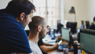Deux hommes travaillent sur des ordinateurs dans un bureau lumineux.
