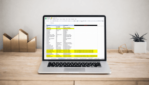 Ordinateur portable avec tableur ouvert, sur un bureau avec plante et décorations.