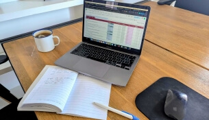 Ordinateur portable sur une table, avec cahier, stylo et tasse de café.
