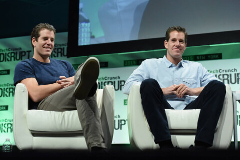 Les jumeaux Winklevoss sur scène assis sur des fauteuils lors d'un évènement tech